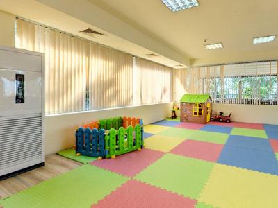 Lichte kinderspeelruimte met kleurrijke vloermatten, speelhuisje en luchtontvochtiger.