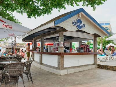 Puesto de bar de cócteles abierto con área de asientos y huéspedes en entorno tropical al aire libre.