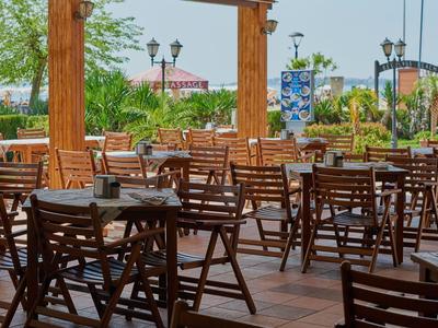 Leeg buitenterras met houten tafels en stoelen bij een hotel of restaurant.