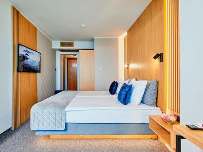 Modern hotelkamer met tweepersoonsbed, houten wandpanelen en flatscreen-tv.