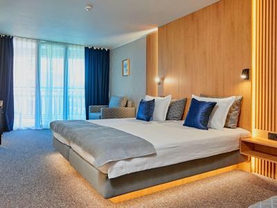 Moderne hotelkamer met tweepersoonsbed, blauwe gordijnen en houten accentmuur