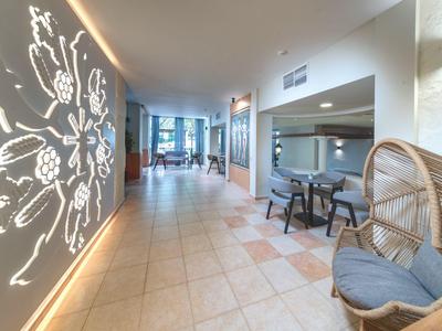 Pasillo de hotel con pared iluminada decorativa y área de asientos con sillas