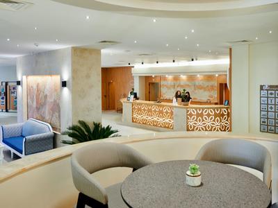 Lichte hotelkamer met ronde tafel, stoelen en receptie op de achtergrond.