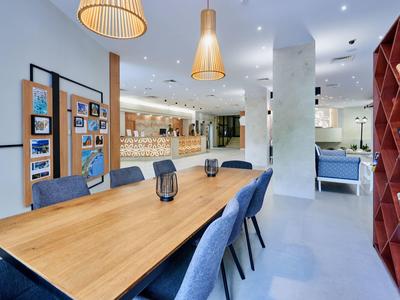 Moderne zithoek met een lange houten tafel, blauwe stoelen en decoratie in een open ruimte.