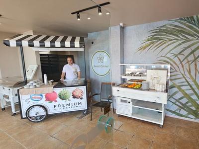 Verkoopstand met surfplank en fruit in een lichte, moderne kamer met muurschildering.