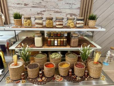 Plank met verschillende specerijen en droge goederen in decoratieve potten in een hotelkeuken