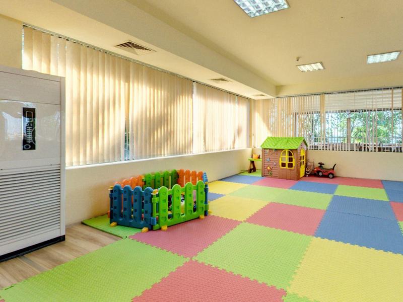 Lichte kinderspeelruimte met kleurrijke vloermatten, speelhuisje en luchtontvochtiger.