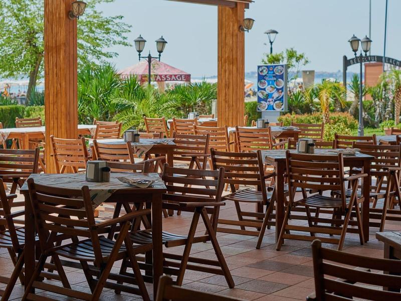 Leeg buitenterras met houten tafels en stoelen bij een hotel of restaurant.