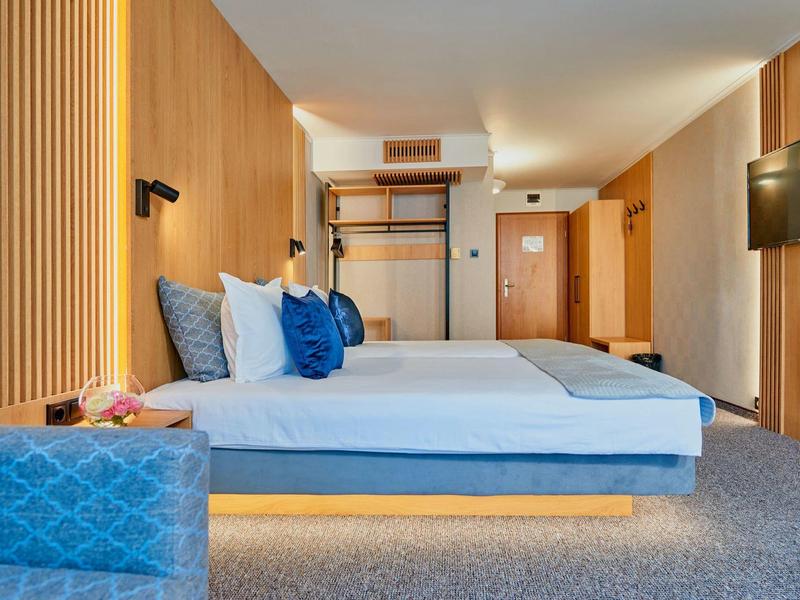 Modern hotelkamer met twee bedden, houten bekleding en een tapijtvloer.