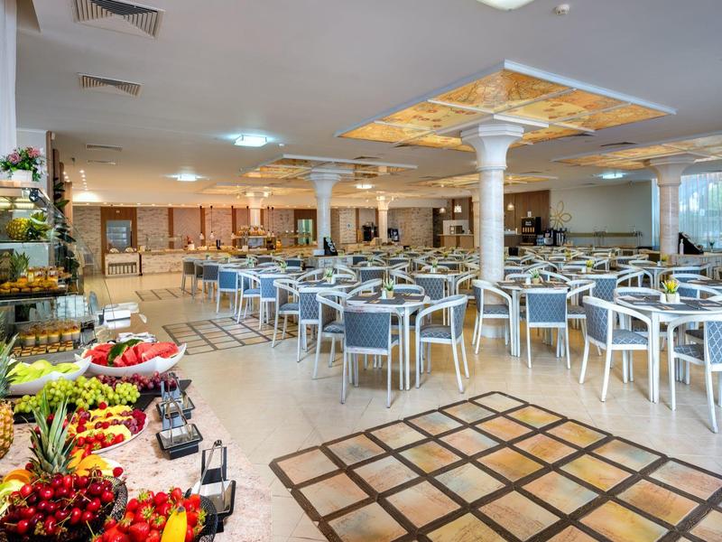 Grote moderne eetzaal met veel tafels en een kleurrijke fruitbuffethoek.