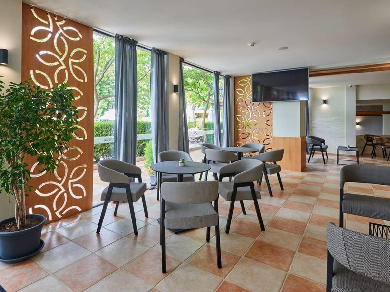 Moderne eetruimte met grijze stoelen, ronde tafels en decoratieve houten wandpaneel