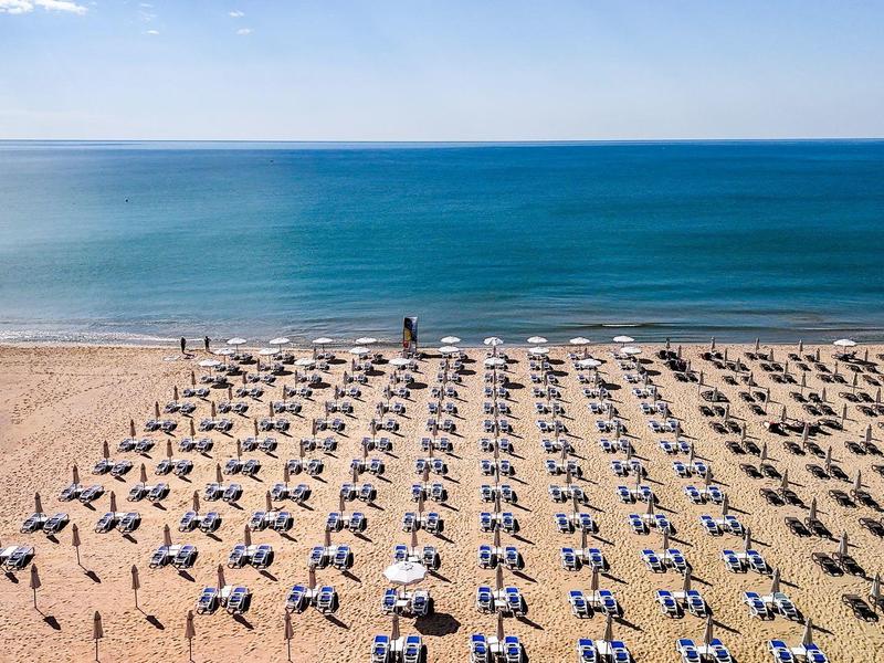 Strand met rijen ligstoelen en parasols aan de blauwe zee