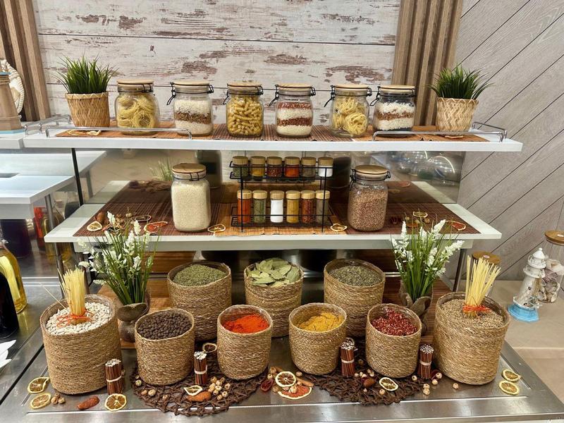 Plank met verschillende specerijen en droge goederen in decoratieve potten in een hotelkeuken