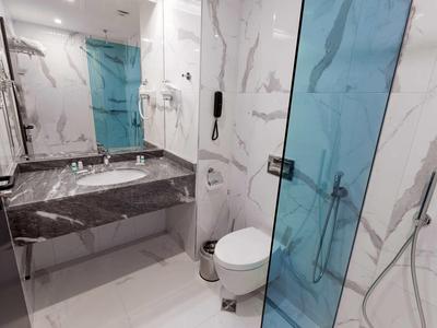 Moderne badkamer met marmeren wanden, toilet en blauwe glazen douche.