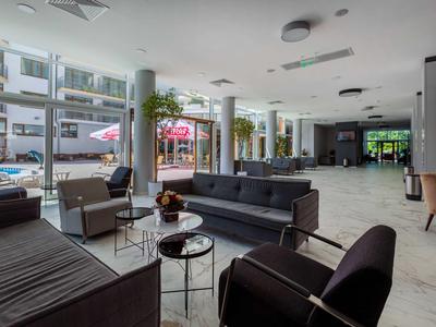 Zona moderna del vestíbulo del hotel con grupos de asientos y grandes ventanas con vistas a la terraza.