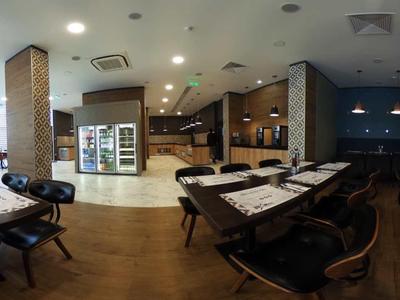 Amplia sala de conferencias moderna con varias mesas, sillas y suelo de madera clara.