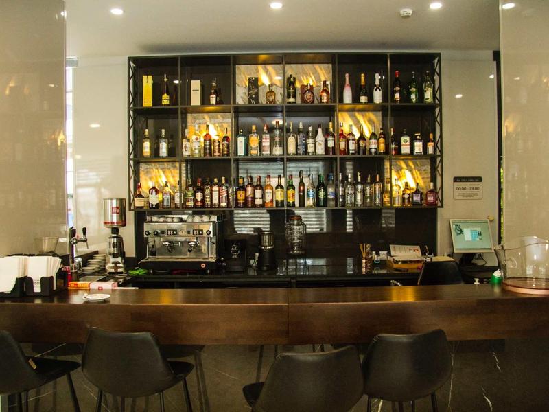 Moderne hotelbar met donkerbruine houten toonbank en goed gevuld drankrek.