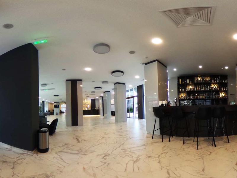 Moderne, ruime hotelbar en lounge met lichte marmeren vloer en zwarte bar