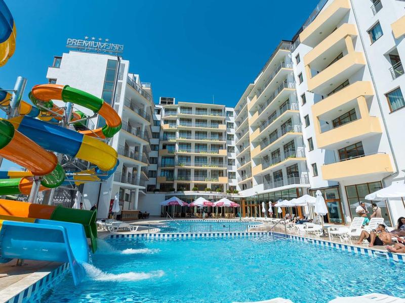 Hotelzwembad met glijbanen en ligstoelen onder een helderblauwe lucht