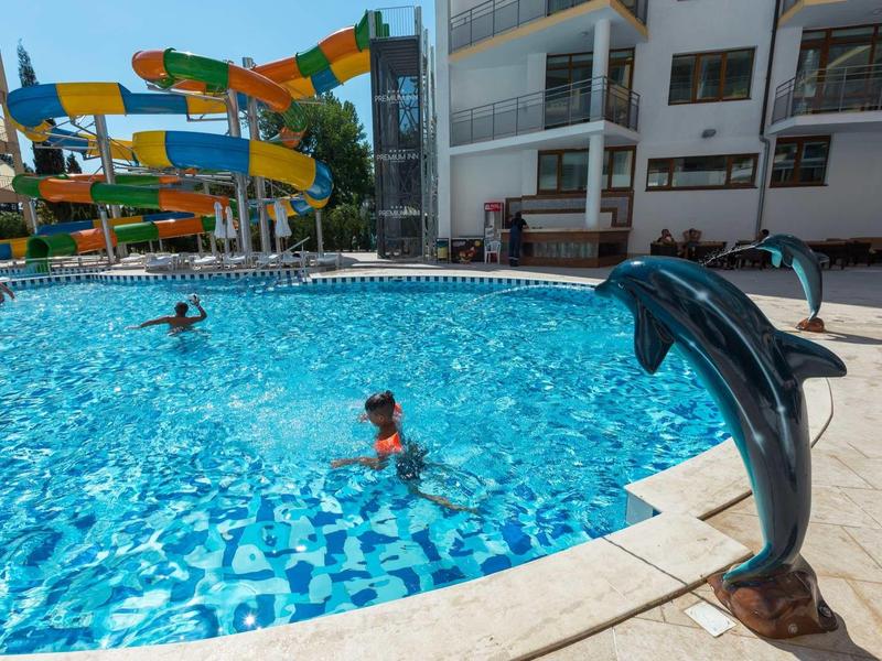 Hotelzwembad met waterglijbanen en een dolfijnfontein op de voorgrond