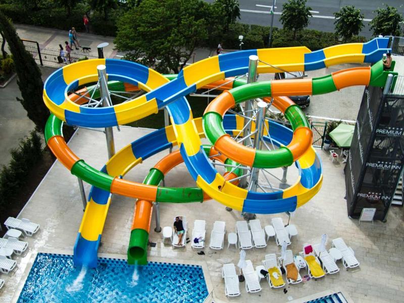 Meerdere kleurrijke waterglijbanen die in een hotelzwembad uitkomen