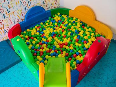 Kleurrijk ballenbad met een gele glijbaan in een speelruimte voor kinderen.