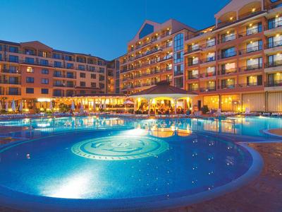 Großes Hotel mit beleuchtetem Außenpool und Sonnenschirmen bei klarem Abendhimmel.