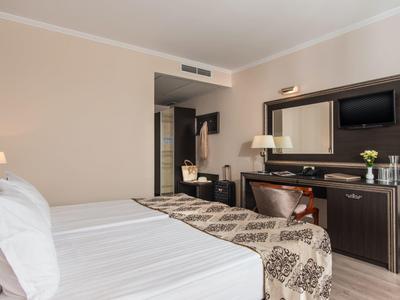 Hotelkamer met tweepersoonsbed, bureau, flatscreen-tv en neutrale inrichting.