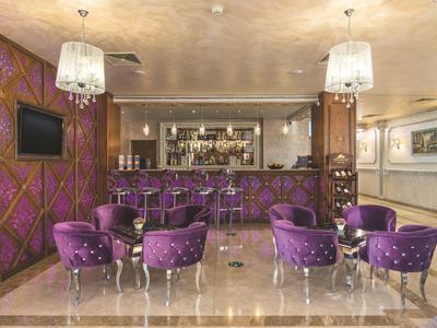 Elegante hotelbar met paarse stoelen en glanzende marmeren vloer in een luxe omgeving.