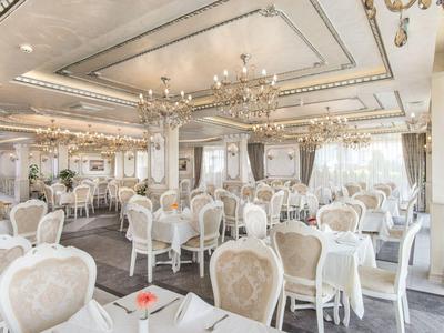 Lichte, elegante eetzaal met witte stoelen en kroonluchters in een hotel.