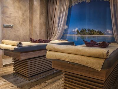 Elegante spa-ruimte met twee massagetafels en uitzicht op een verlicht zwembad.