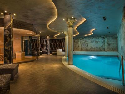 Moderne wellnessruimte met zwembad, designverlichting en gezellige zitplaatsen.