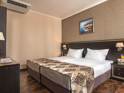 Modern hotelkamer met tweepersoonsbed, nachtkastjes en airconditioning.