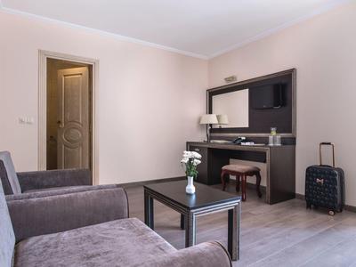 Moderne hotelkamer met bank, salontafel, flatscreen-tv en koffer naast een sidetable