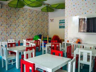 Kleurrijk ingerichte lounge met witte en rode stoelen en kleine tafels.