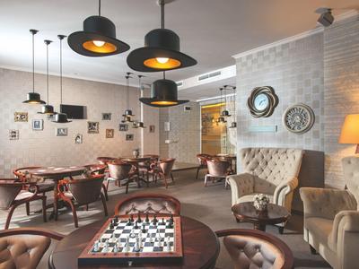 Lichte hotelkamer met gezellige zitplaatsen, tafels en moderne plafondlampen.