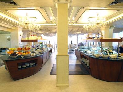 Luxe hotelbuffet met diverse gerechten op elegante houten tafels onder kroonluchters.