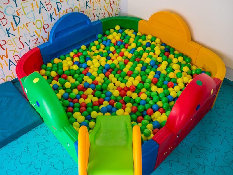 Kleurrijk ballenbad met een gele glijbaan in een speelruimte voor kinderen.