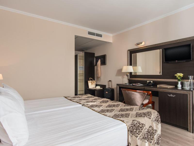 Hotelkamer met tweepersoonsbed, bureau, flatscreen-tv en neutrale inrichting.