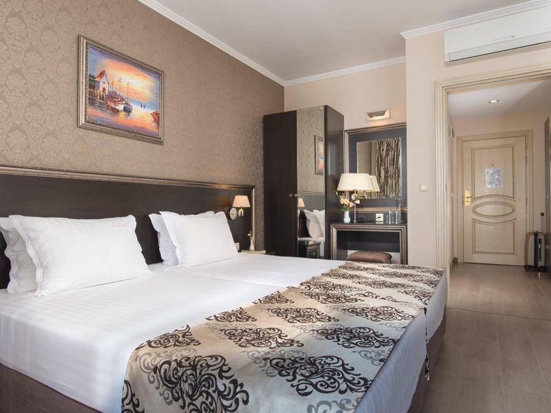 Modern hotelkamer met tweepersoonsbed, bureau en airconditioning in neutrale tinten.