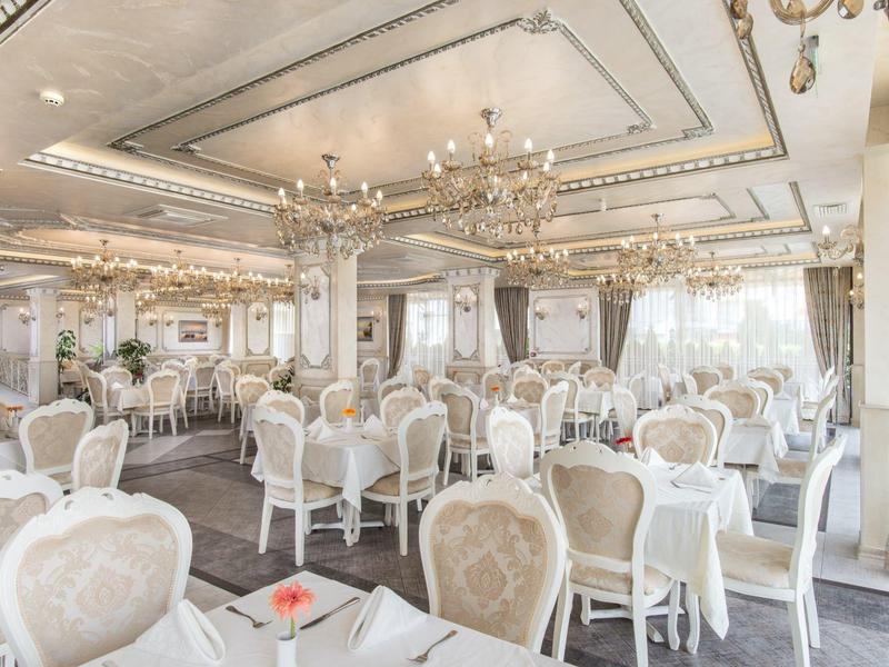 Elegante eetkamer met witte stoelen, tafels en kandelaars in een hotel.