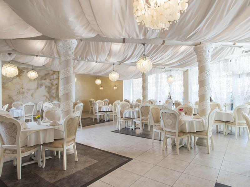 Elegant restaurant met crèmekleurige stoelen, witte tafels en zachte verlichting.