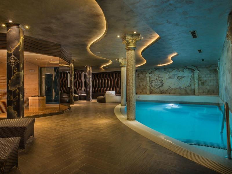 Moderne wellnessruimte met zwembad, designverlichting en gezellige zitplaatsen.