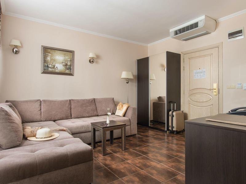 Gezellige hotelkamer met bank, tafel, koffer en airconditioning aan de muur.