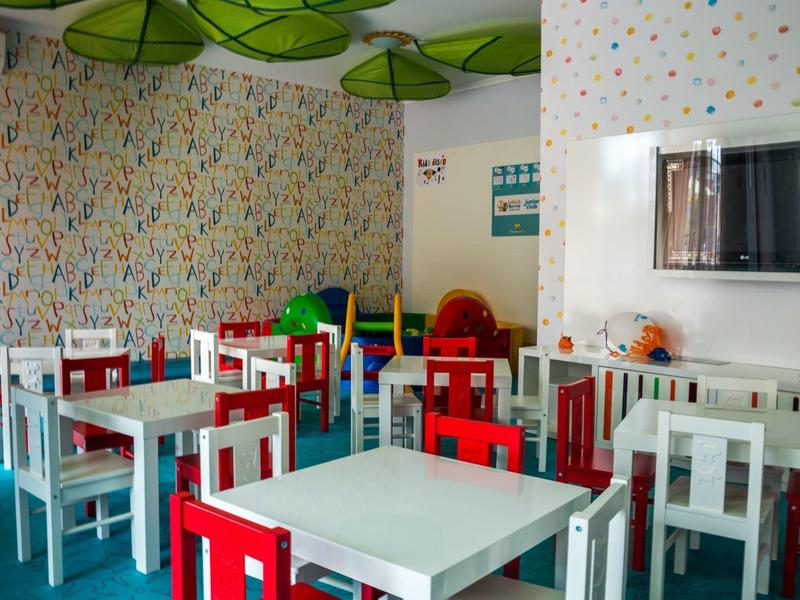 Kleurrijk ingerichte lounge met witte en rode stoelen en kleine tafels.