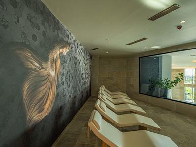 Ontspanningsruimte met comfortabele ligstoelen, groot raam en muur met abstract patroon.