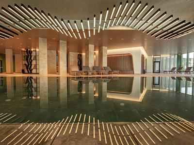 Moderne binnenzwembad met houten plafond en grote ramen in een hotel.