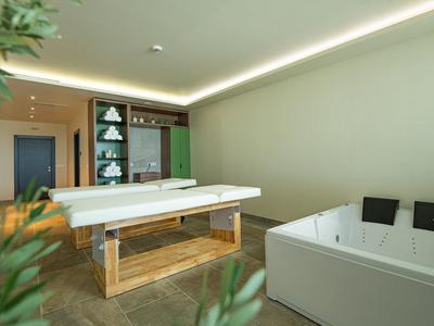 Moderne wellnessruimte met massagetafel en badkuip, licht en rustig ingericht.