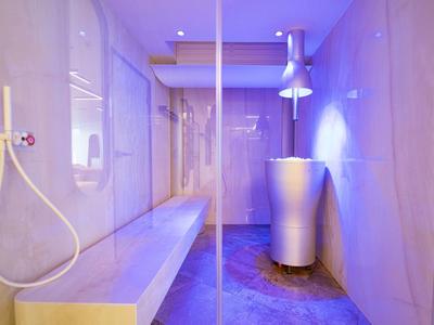 Moderne wellnessruimte met douche, houten bank en gekleurde verlichting