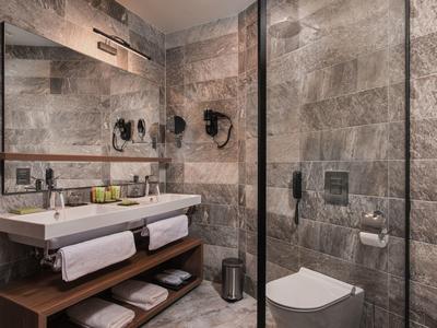 Moderne badkamer met natuurstenen muren, dubbele wastafels en inloopdouche.